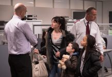 Actor Hayley Squires and two child actors surrounded by two men dressed as security guards in a scene of the film 'I, Daniel Blake'