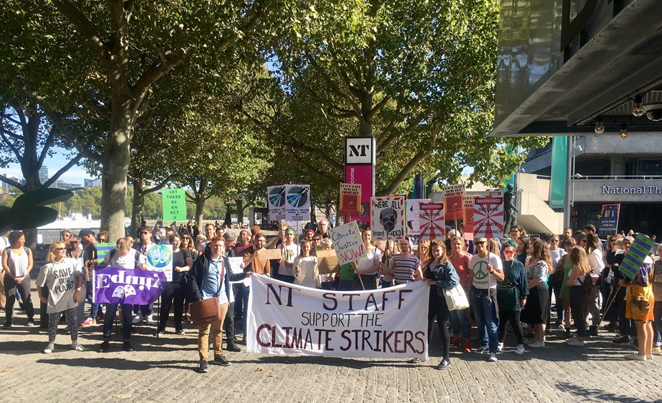 A group of artworkers stand with a banner outdoors on the Southbank in London