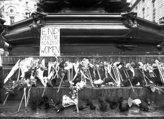Flowers and a sign reading 'end violence against women'
