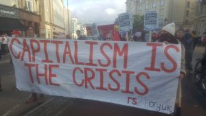 Banner reads: capitalism is the crisis