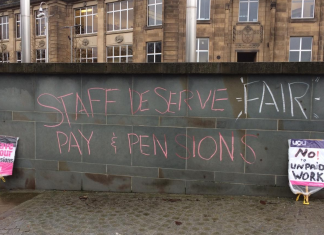 Placards. Chalk on wall reads: staff deserve fair pay & pensions