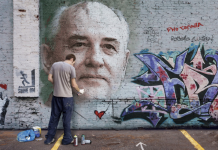 Man spray paints image of Gorachev on a wall