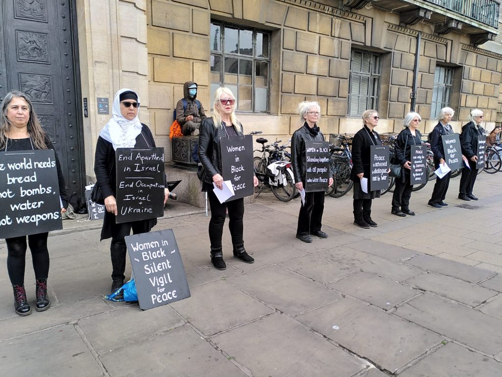 Women dressed in black stand in a line with placards
