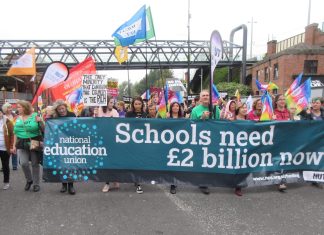 NEU members march with banner reading "schools need £2 billion now"
