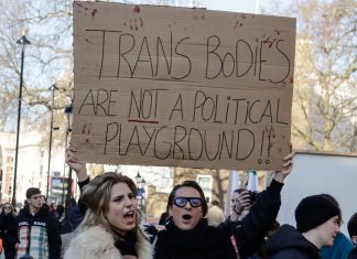 People hold placard reading "trans bodies are not a political playground"