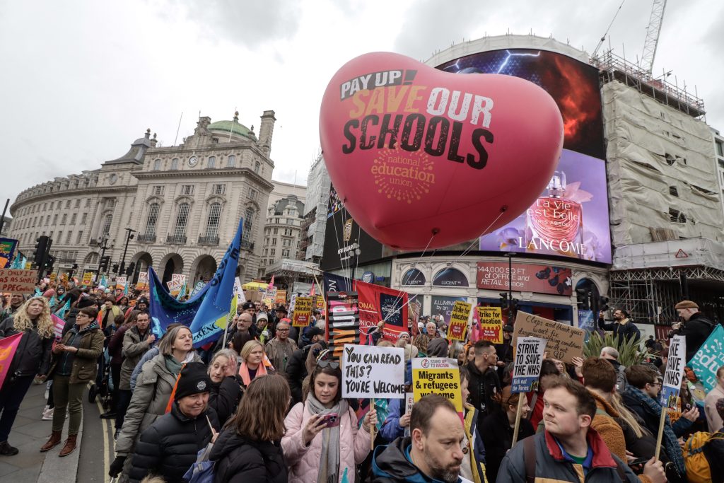 la folla marcia a Londra con un grande pallone NEU a forma di cuore