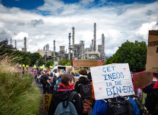 climate activists march toward the refinery