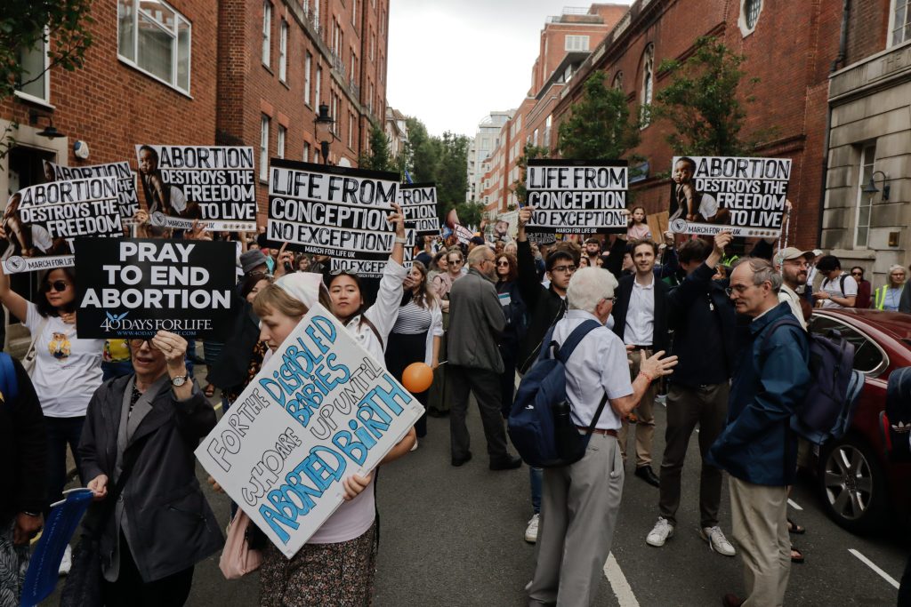 Демонстранты против абортов держат различные плакаты.